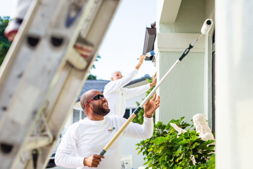 Painter refreshing exterior house walls and trim