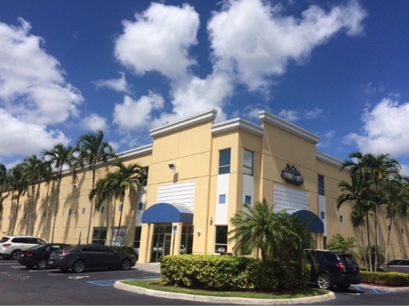 Doral commercial building with yellow exterior walls and blue entrance awnings