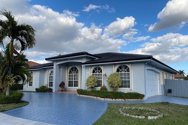 Painting Contractor Doral FL | Gonzalez Painting & Waterproofing INC Doral home with a light exterior, dark tile roof and blue driveway